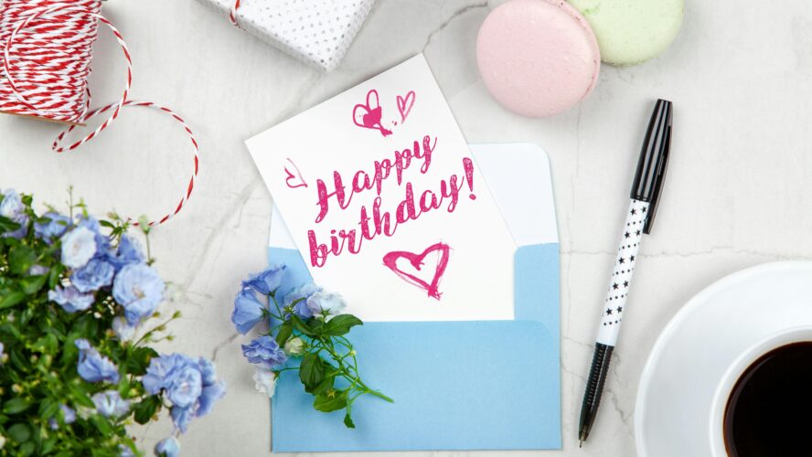 A birthday card on a table that reads 'Happy Birthday' in a blue envelope