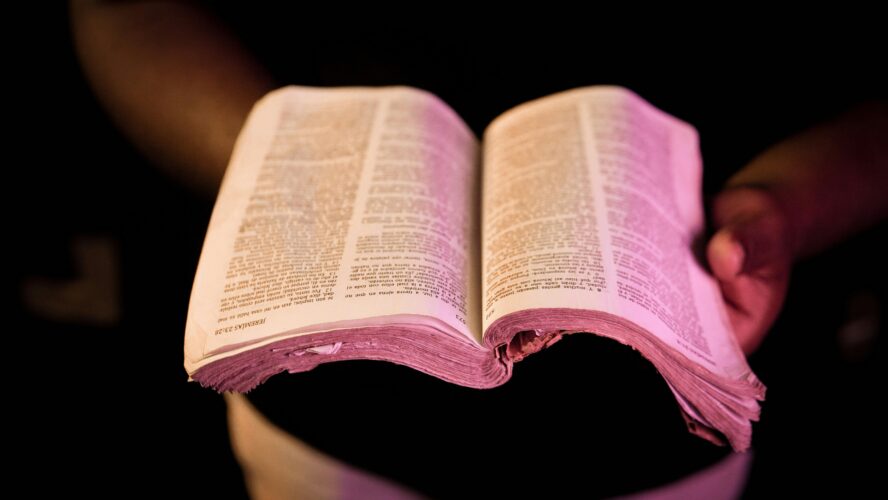 Black hands holding a well-worn Bible, open. Photography by Orlando Allo.