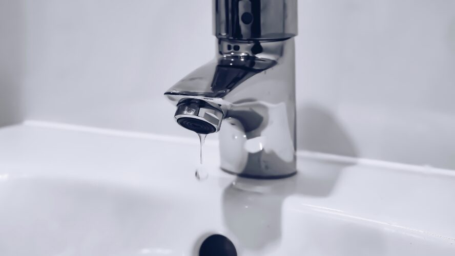 A dripping silver tap in a bathroom sink