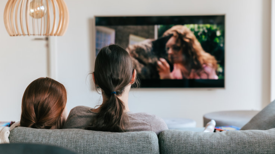 Image of the back of a sofa with a mum and daughter sat together, watching TV