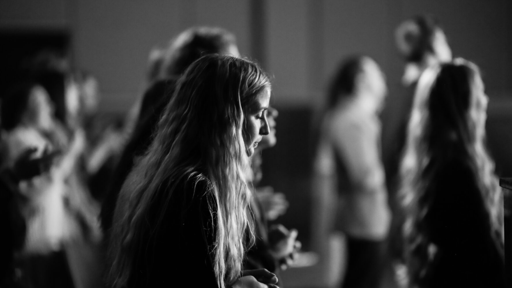 Black and white photo of a woman with her eyes closed, praying in her church