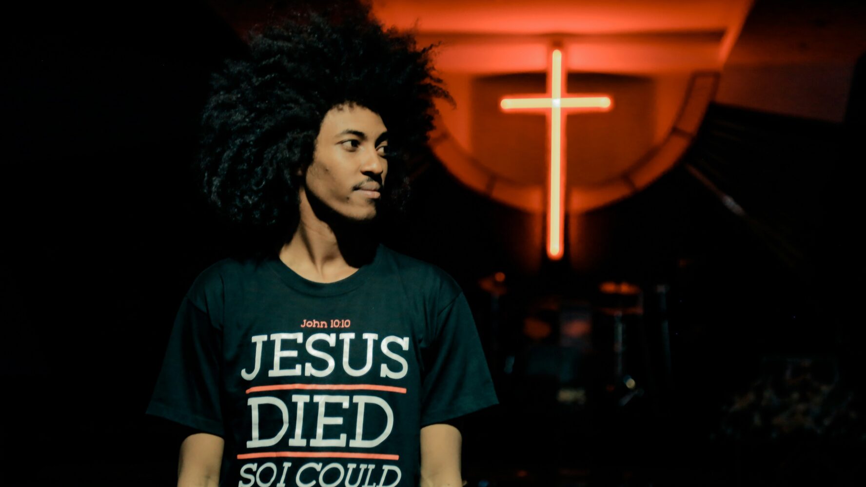 A man stood in front of a lit up cross in church