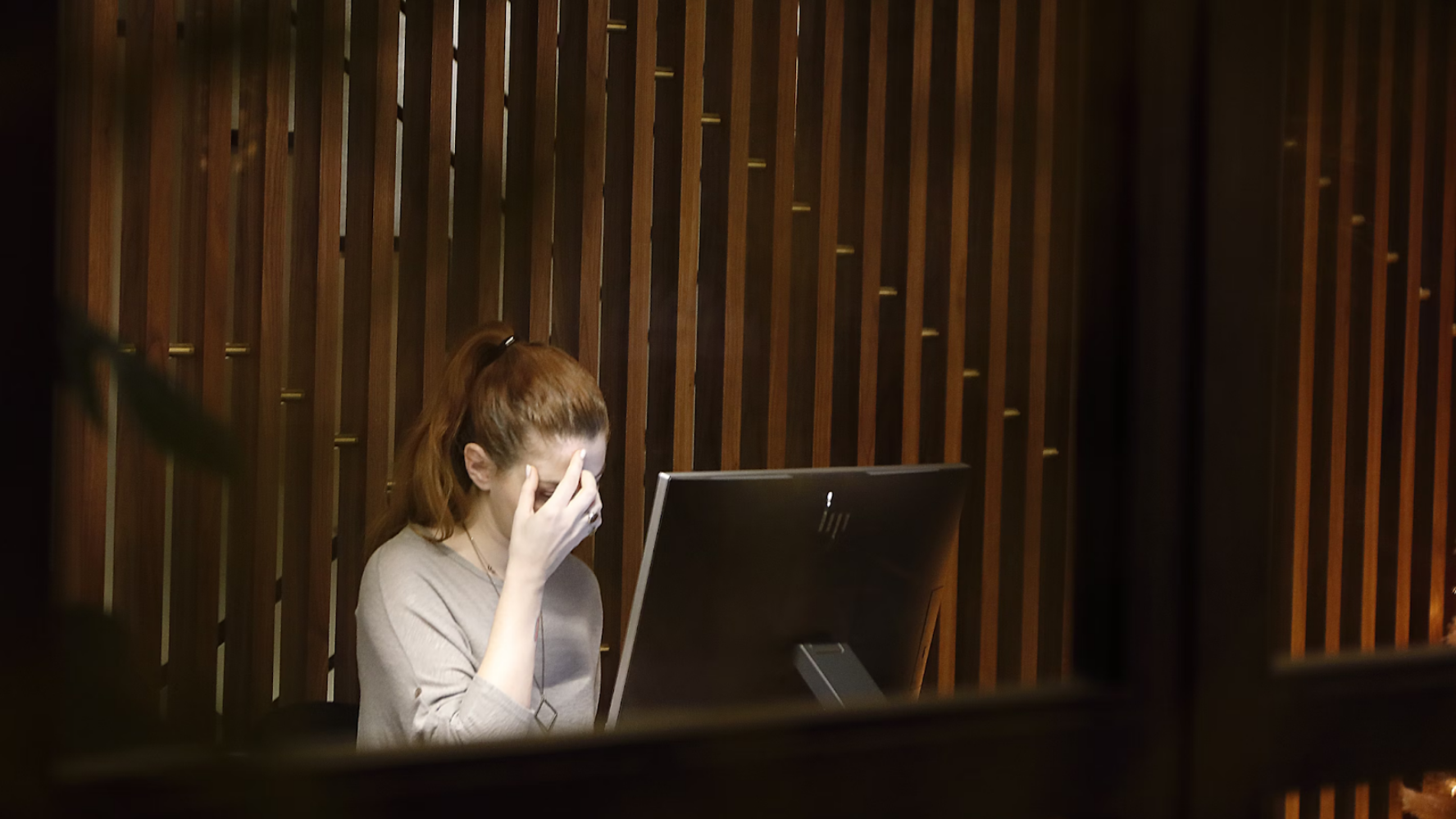 person sat looking at a computer screen with their head in their hands