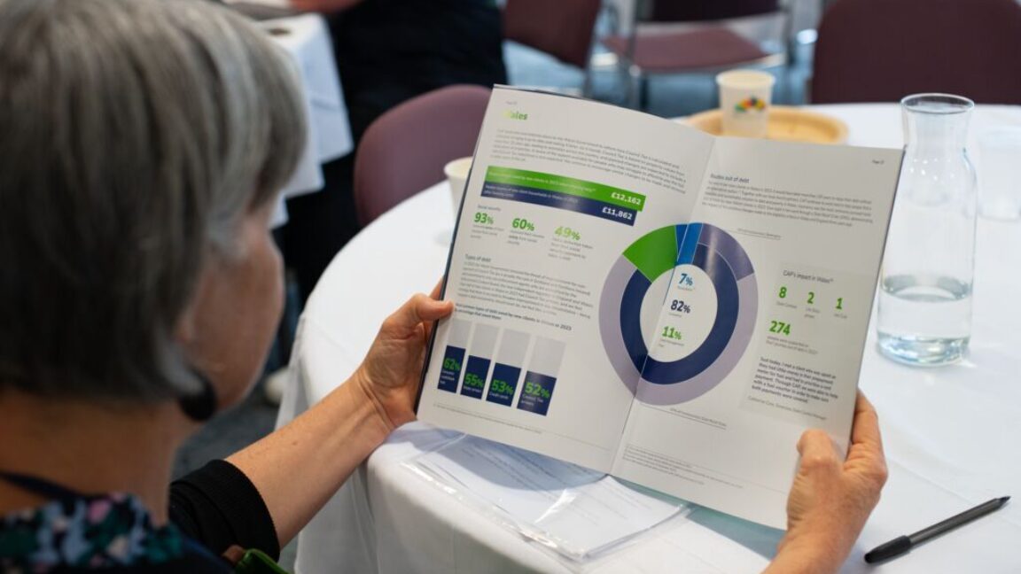 Person sat at a table holding a magazine with different graphs and stats inside