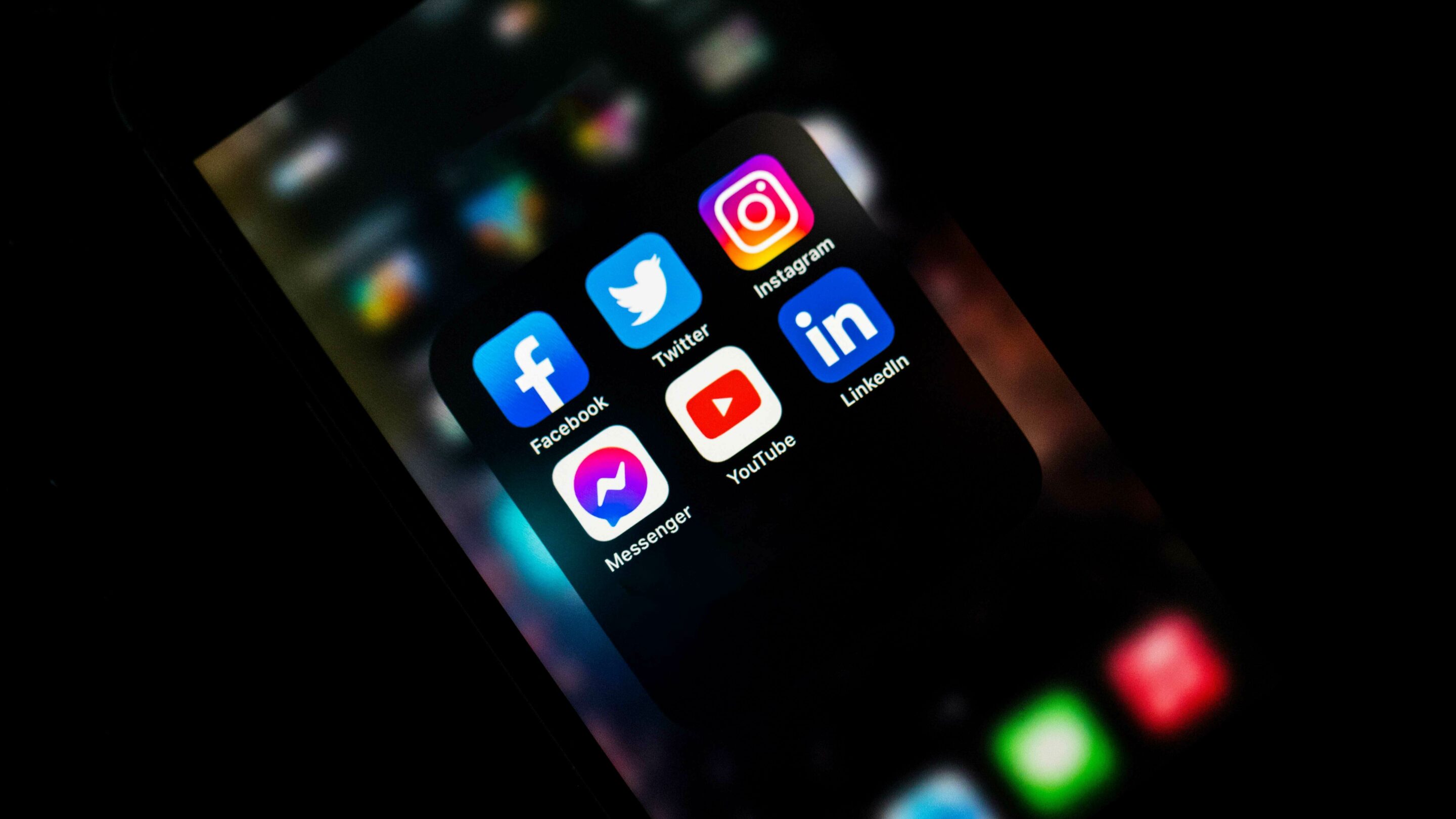 Phone screen lit up showing a folder of social media icons.