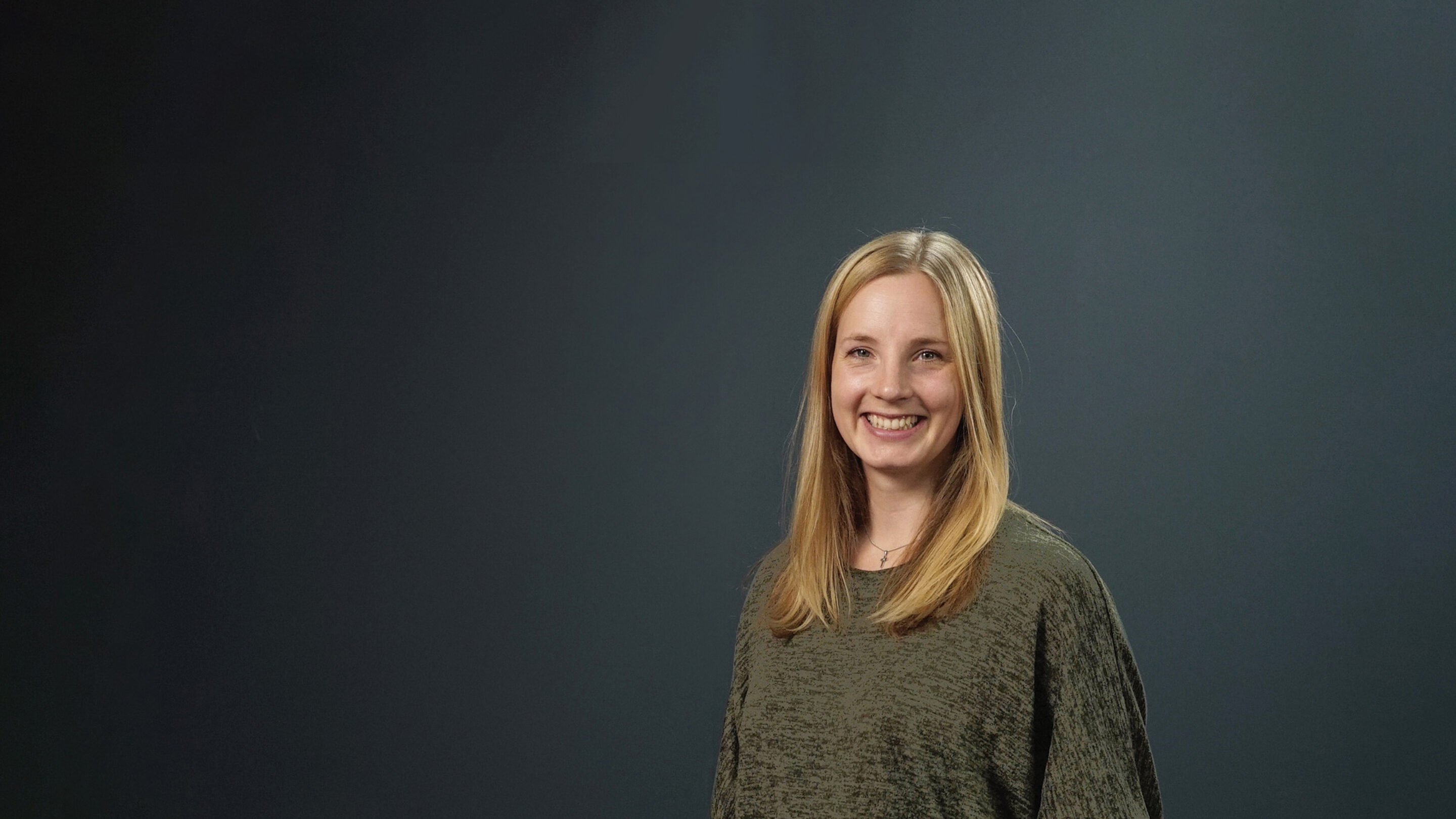 Young woman stood facing forwards smiling broadly at the camera.