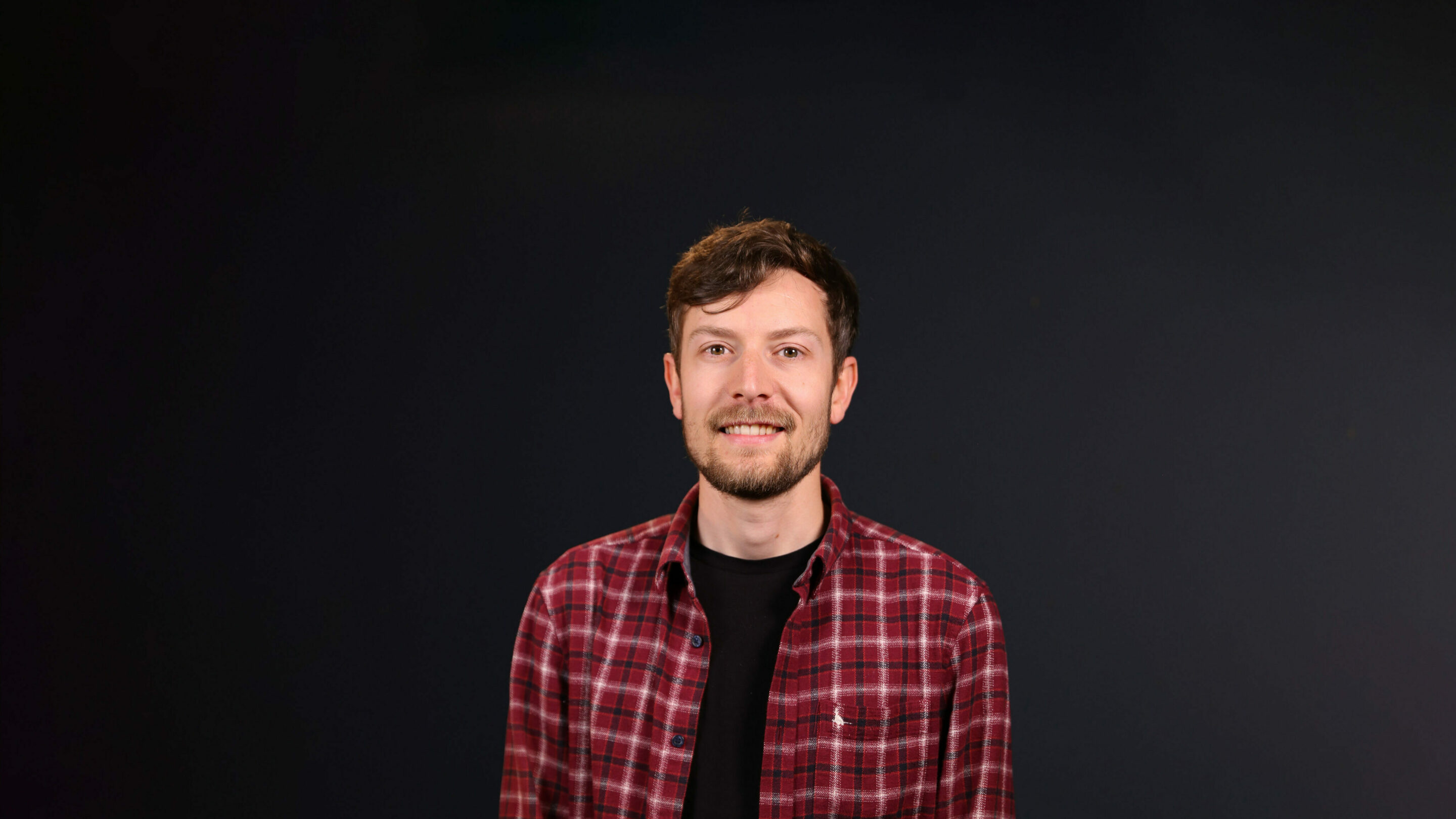 Tall young male stood facing forwards smiling.