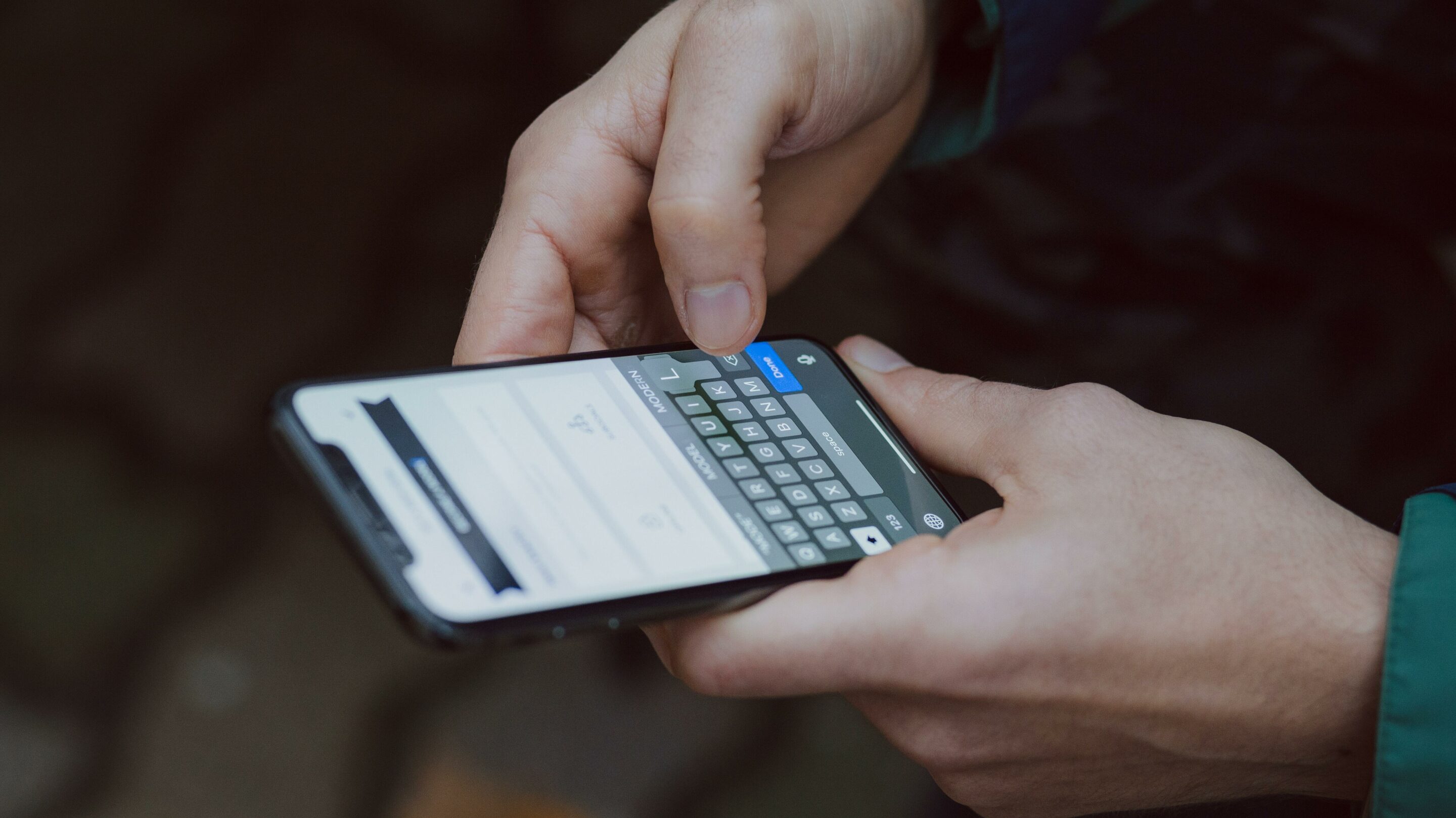 Two hands holding an unlocked mobile phone sending a text.