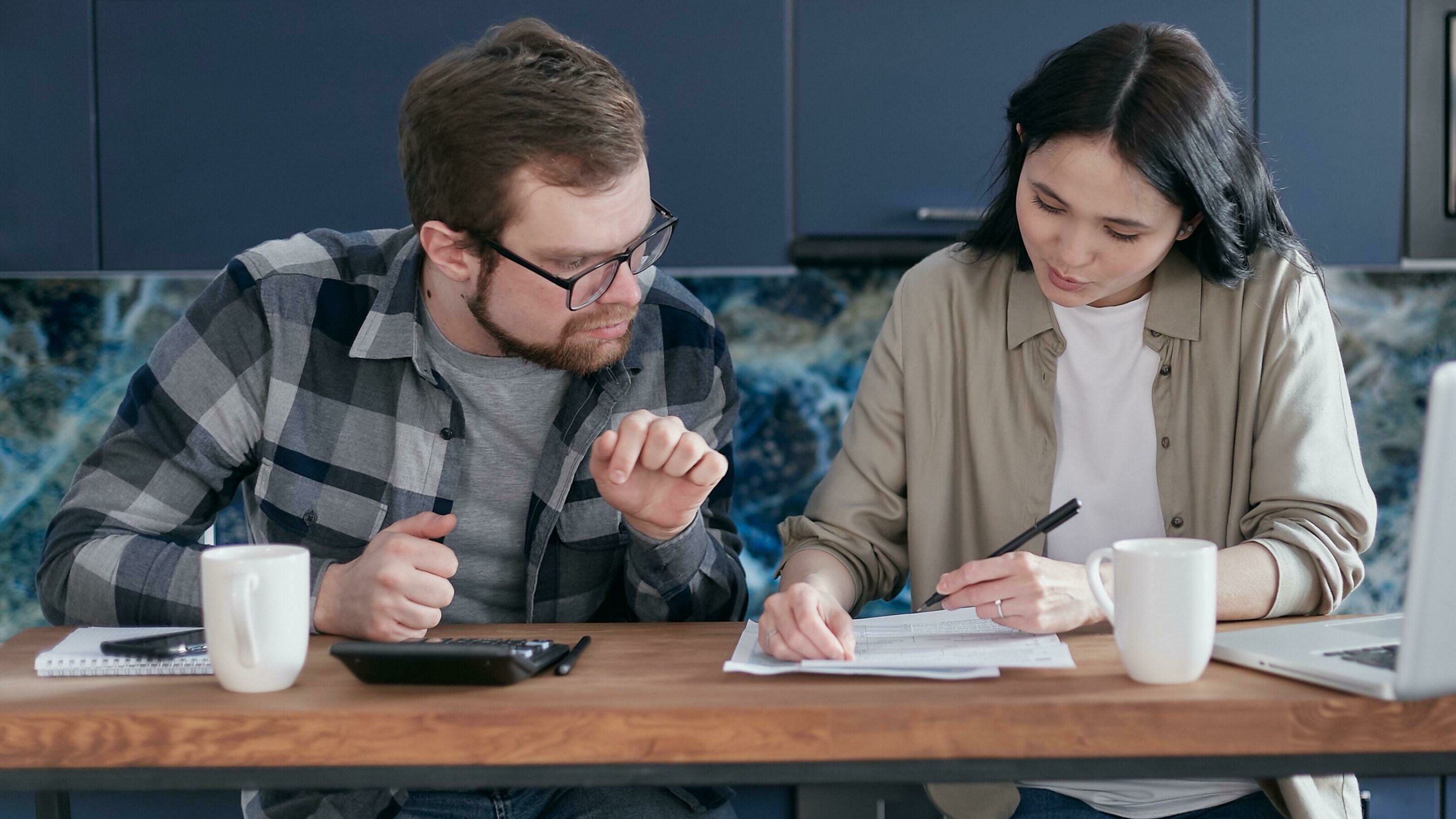 A couple sitting at a table with some papers, working out their debts