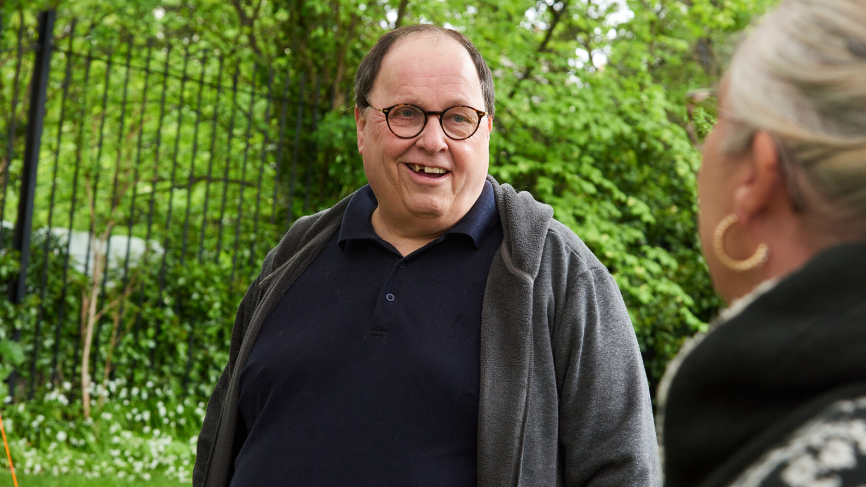 Older male talking to woman outside and smiling.