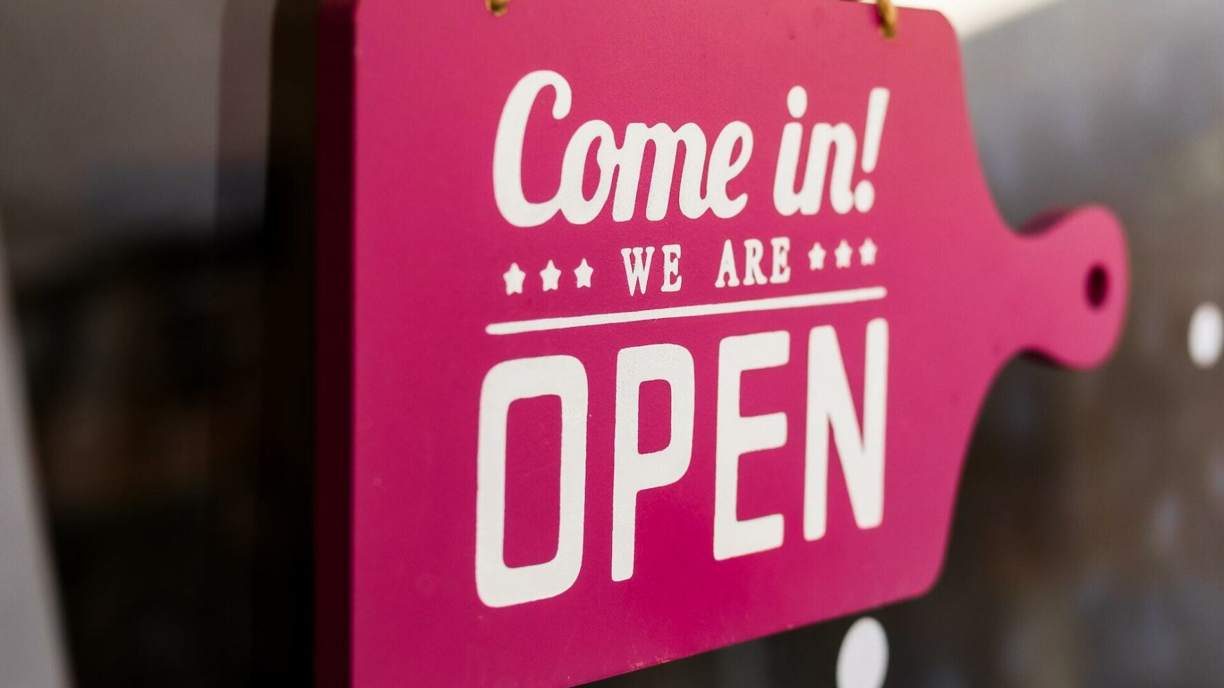 A bright pink sign reads 'come in, we're open'