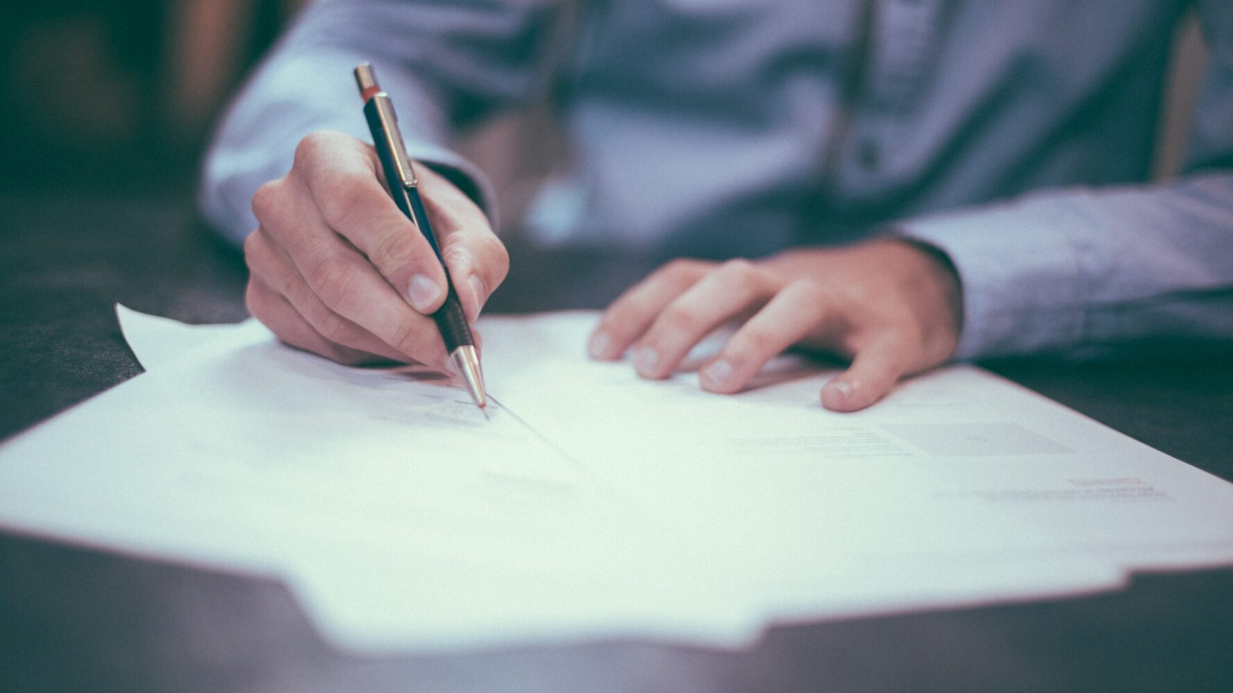 Letter being signed by man holding pen