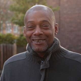 CAP client, Paul, stood outside, wearing a grey jumper and smiling at the camera