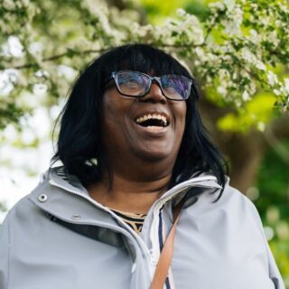 CAP client, Melinda, stood outside in a garden, smiling and looking up at the sky