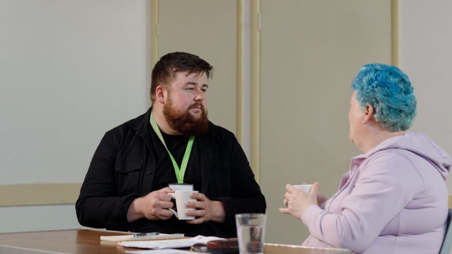 Image of CAP client and her local debt coach, sat at a table and talking to each other
