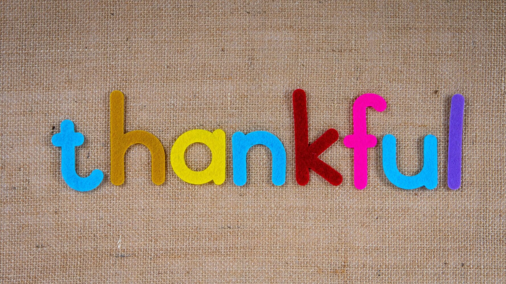 the word thankful is spelled out in colourful letters on a brown background