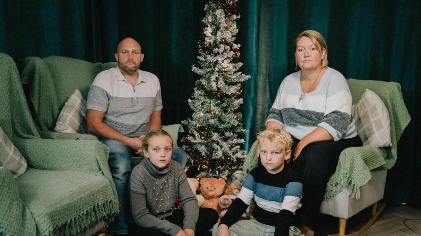Two CAP clients and their two children sat in their living room at Christmas, looking into the camera
