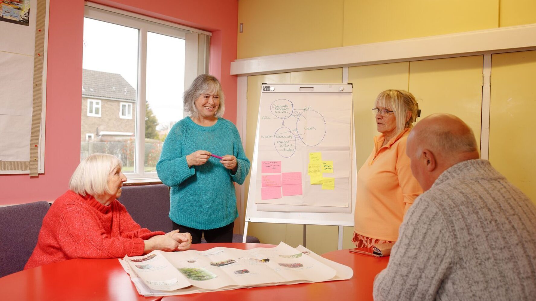 A local church receiving training from CAP to help find ways to help their local community. They are sat around a table writing down ideas on a whiteboard.