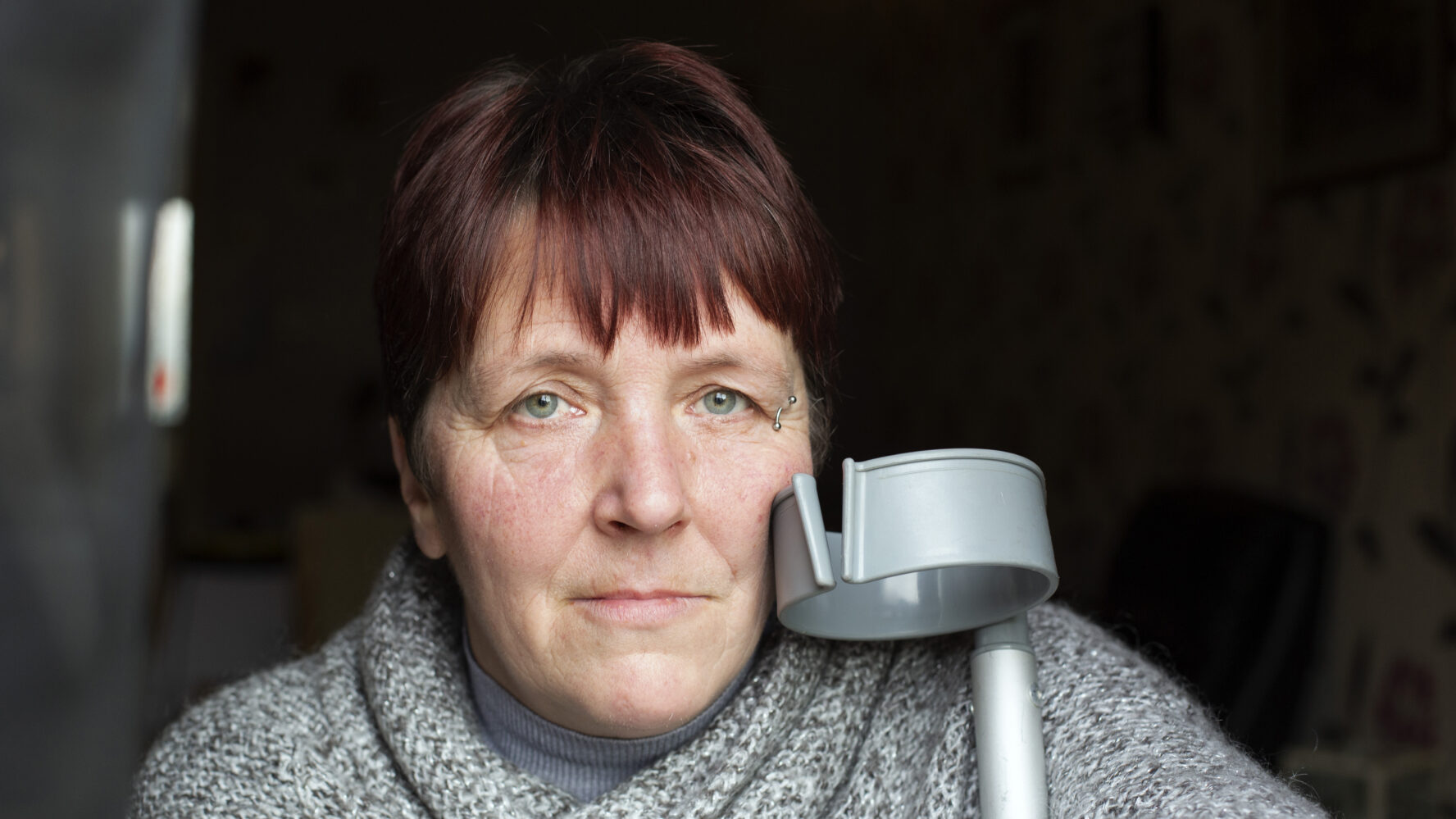 Former CAP client, looks into the camera with her crutch next to her